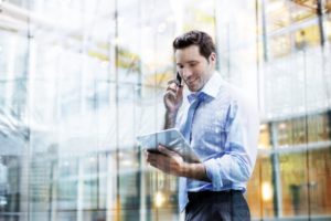 businessman holding an ipad while on phone