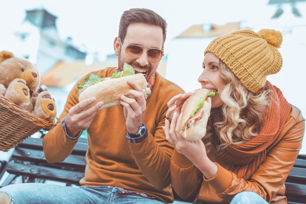 man and woman eating subs