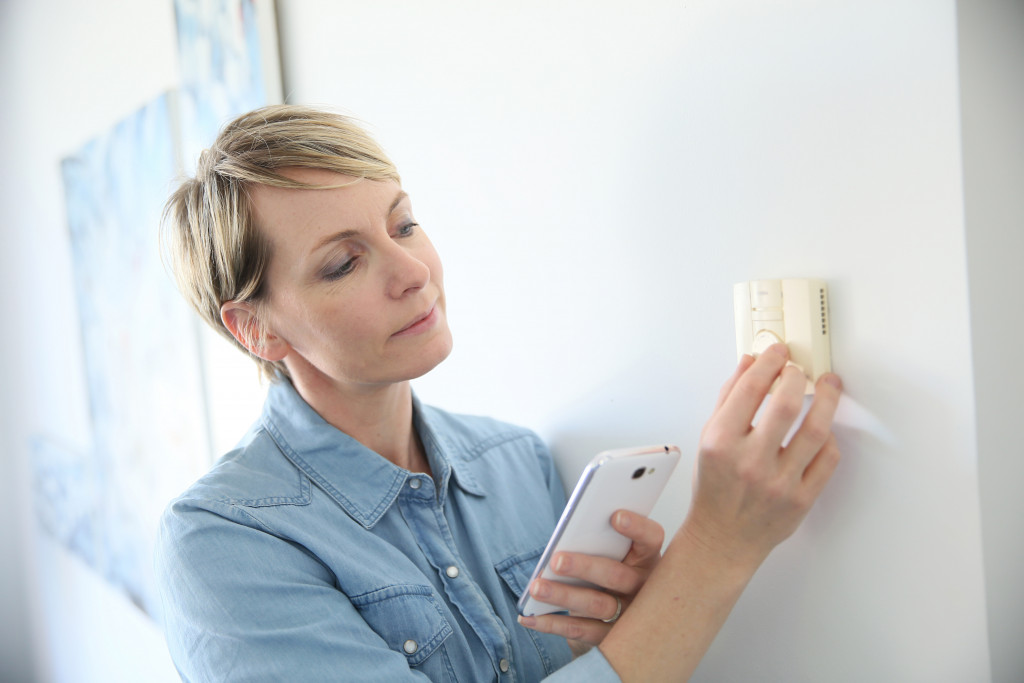 woman adjusting thermostat