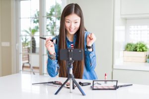 girl broadcasting in front her camera holding a makeup brush