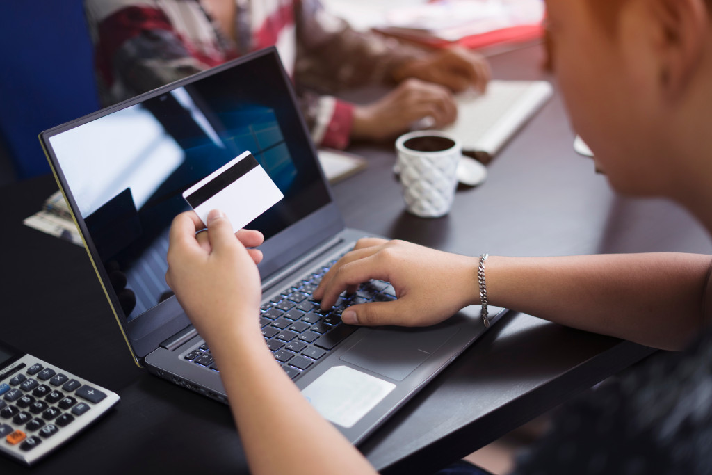 Rear view of a man entering debit cards detail for online purchase 