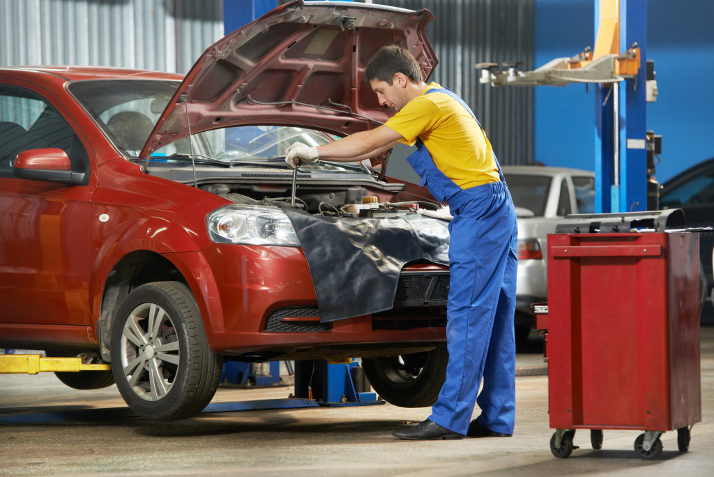 young mechanic working on a red car