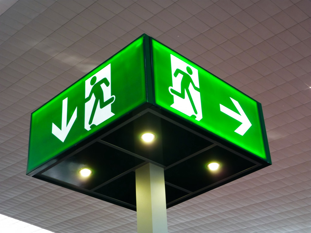 An illuminated emergency exit sign on a ceiling