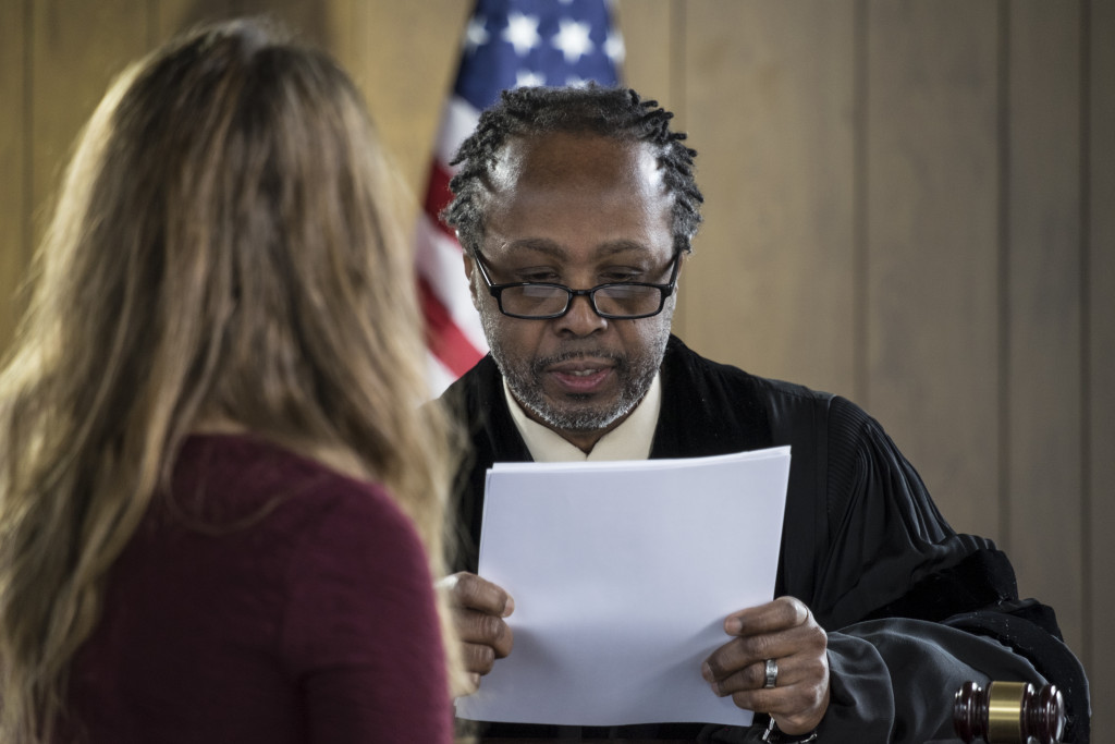 a judge reading document in front of a lawyer in a courtroom