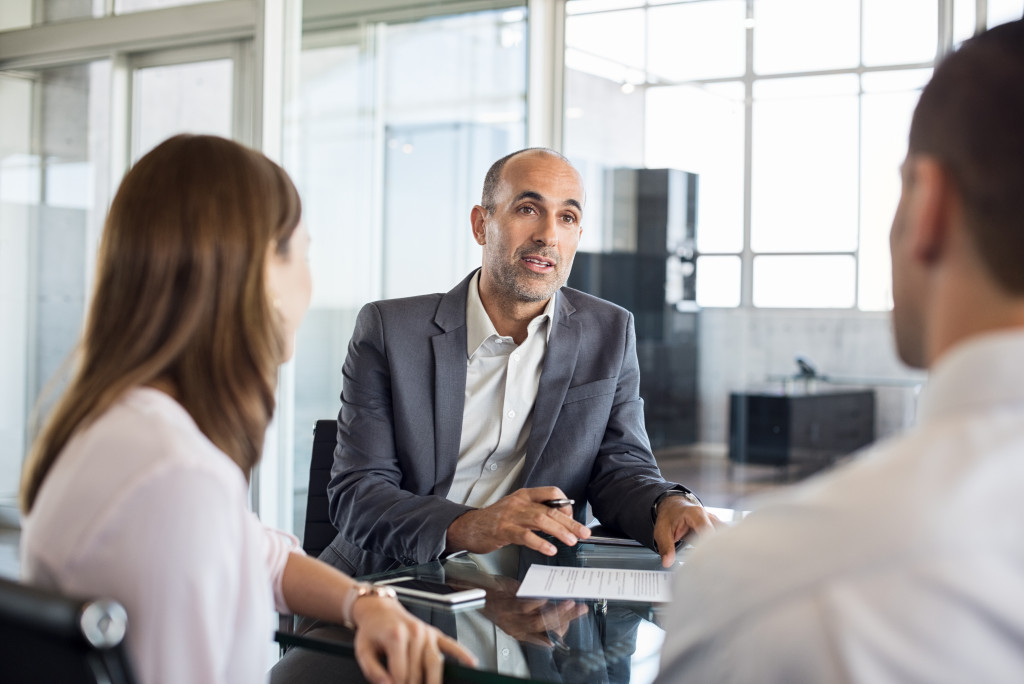 elderly lawyer discussing agreement to couple looking at him