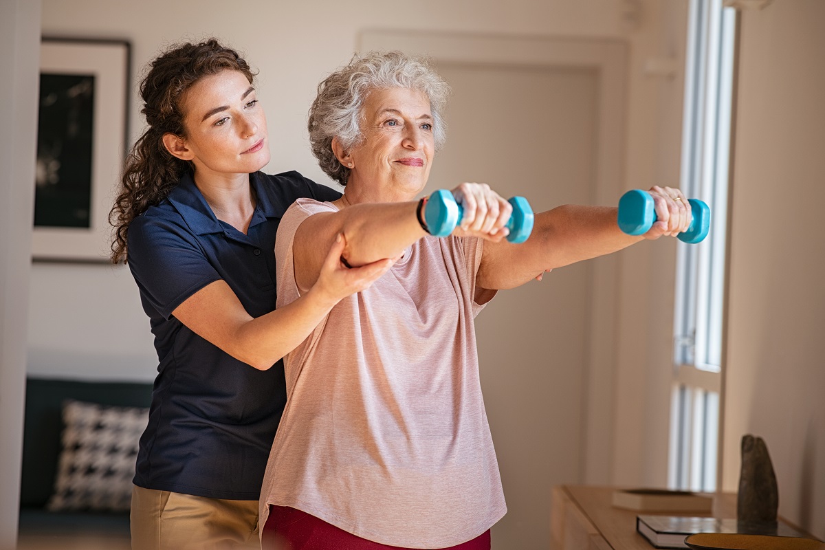 a medical professional assisting an elderly woman on her workout