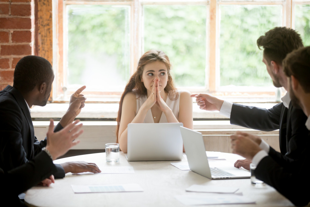 woman listening as mediator to many fighting male office workers