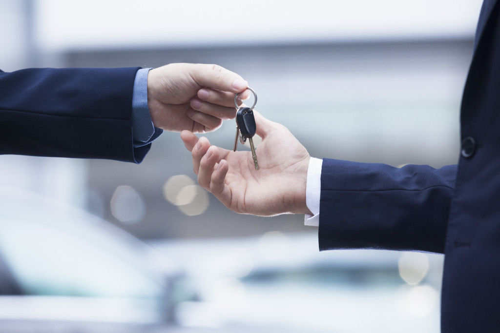 businessman handing company car keys to another employee